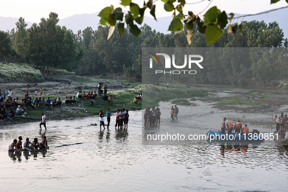 Villagers are watching as SDRF is launching an operation to trace the body of a young man who drowned in Nalla Puhroo while taking a bath on...