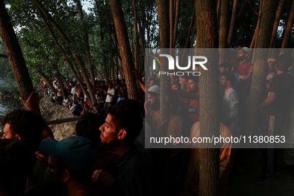 Villagers are watching as SDRF is launching an operation to trace the body of a young man who drowned in Nalla Puhroo while taking a bath on...