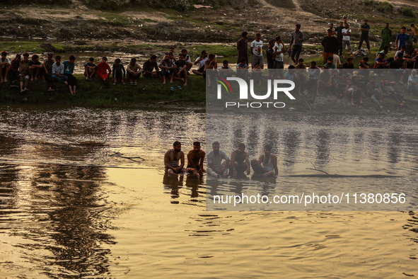 Villagers are watching as SDRF is launching an operation to trace the body of a young man who drowned in Nalla Puhroo while taking a bath on...