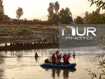 Villagers are watching as SDRF is launching an operation to trace the body of a young man who drowned in Nalla Puhroo while taking a bath on...