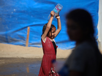 A displaced Palestinian girl is cooling herself with water outside her tent during a heat wave in Deir al-Balah in the central Gaza Strip on...