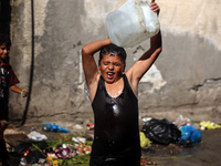 A displaced Palestinian boy is cooling himself with water outside his tent during a heat wave in Deir al-Balah in the central Gaza Strip on...