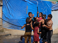 Displaced Palestinian children are playing with water outside their tents during a heat wave in Deir al-Balah in the central Gaza Strip on J...