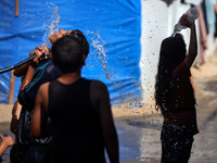 Displaced Palestinian children are playing with water outside their tents during a heat wave in Deir al-Balah in the central Gaza Strip on J...