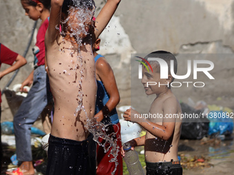 A displaced Palestinian boy is cooling himself with water outside his tent during a heat wave in Deir al-Balah in the central Gaza Strip on...