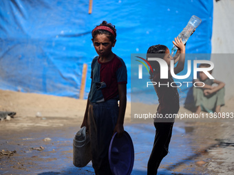 A displaced Palestinian girl is cooling herself with water outside her tent during a heat wave in Deir al-Balah in the central Gaza Strip on...