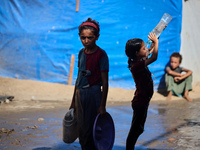 A displaced Palestinian girl is cooling herself with water outside her tent during a heat wave in Deir al-Balah in the central Gaza Strip on...