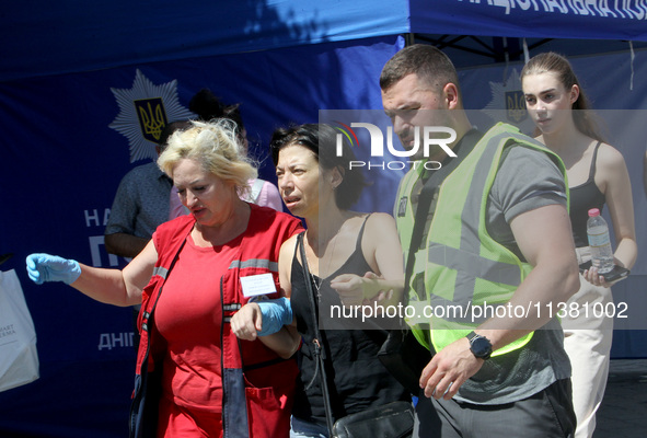 A police officer and paramedic are supporting a woman near a shopping mall during the Russian missile strike in Dnipro, Ukraine, on July 3,...