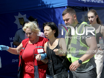 A police officer and paramedic are supporting a woman near a shopping mall during the Russian missile strike in Dnipro, Ukraine, on July 3,...