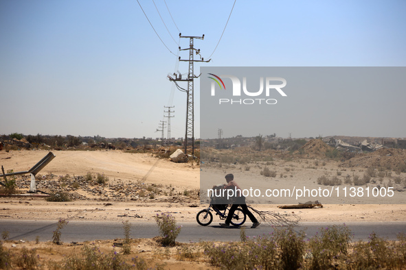 A Palestinian boy is walking with his bicycle loaded with firewood on Salah El Din Street in Deir al-Balah in the central Gaza Strip on July...