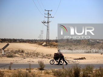 A Palestinian boy is walking with his bicycle loaded with firewood on Salah El Din Street in Deir al-Balah in the central Gaza Strip on July...