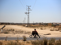 A Palestinian boy is walking with his bicycle loaded with firewood on Salah El Din Street in Deir al-Balah in the central Gaza Strip on July...