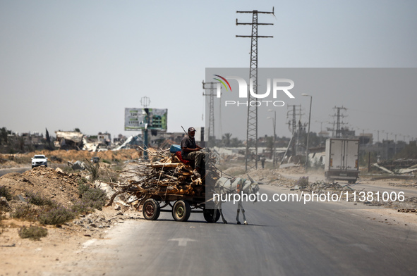 A Palestinian man is using a donkey cart to transport firewood on Salah El Din Street in Deir al-Balah in the central Gaza Strip on July 3,...