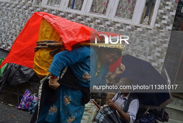 A woman is carrying heavy loads on her head in Darjeeling, India, on July 2, 2024. People are shopping in a vegetable market in Darjeeling,...