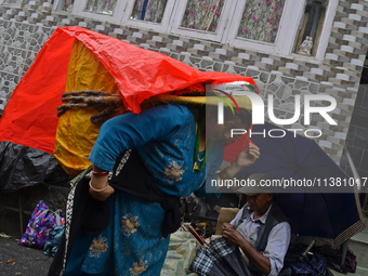 A woman is carrying heavy loads on her head in Darjeeling, India, on July 2, 2024. People are shopping in a vegetable market in Darjeeling,...