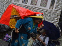 A woman is carrying heavy loads on her head in Darjeeling, India, on July 2, 2024. People are shopping in a vegetable market in Darjeeling,...