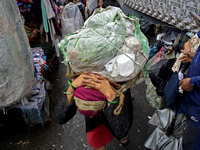 A woman is carrying heavy loads on her head in Darjeeling, India, on July 2, 2024. People are shopping in a vegetable market in Darjeeling,...