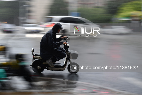 A citizen is riding in a rainstorm in Fuyang, China, on July 4, 2024. On the same day, Fuyang city in Anhui province is suffering heavy rain...