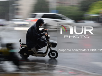 A citizen is riding in a rainstorm in Fuyang, China, on July 4, 2024. On the same day, Fuyang city in Anhui province is suffering heavy rain...