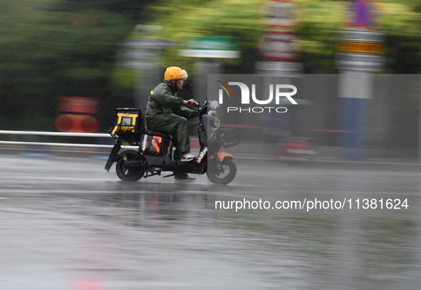 A citizen is riding in a rainstorm in Fuyang, China, on July 4, 2024. On the same day, Fuyang city in Anhui province is suffering heavy rain...