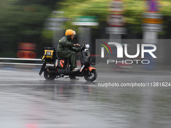 A citizen is riding in a rainstorm in Fuyang, China, on July 4, 2024. On the same day, Fuyang city in Anhui province is suffering heavy rain...