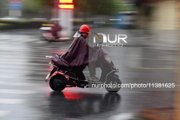 A citizen is riding in a rainstorm in Fuyang, China, on July 4, 2024. On the same day, Fuyang city in Anhui province is suffering heavy rain...