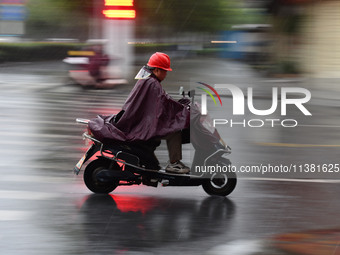 A citizen is riding in a rainstorm in Fuyang, China, on July 4, 2024. On the same day, Fuyang city in Anhui province is suffering heavy rain...