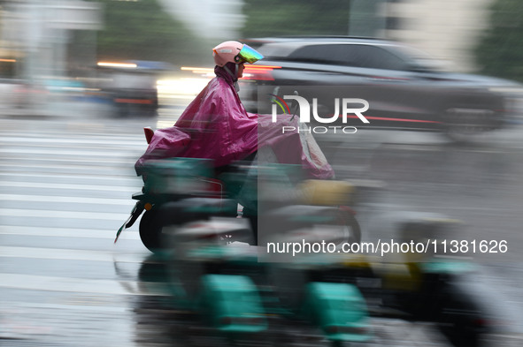 A citizen is riding in a rainstorm in Fuyang, China, on July 4, 2024. On the same day, Fuyang city in Anhui province is suffering heavy rain...