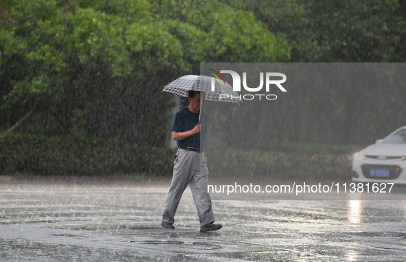 A citizen is walking in the rain in Fuyang, China, on July 4, 2024. On the same day, Anhui Fuyang city is suffering heavy rain. 