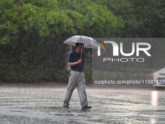 A citizen is walking in the rain in Fuyang, China, on July 4, 2024. On the same day, Anhui Fuyang city is suffering heavy rain. (