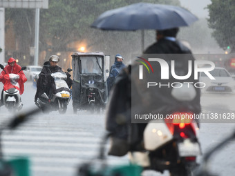 A citizen is riding in a rainstorm in Fuyang, China, on July 4, 2024. On the same day, Fuyang city in Anhui province is suffering heavy rain...