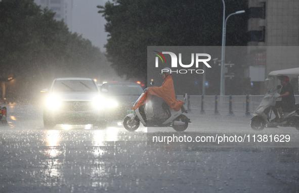 A citizen is riding in a rainstorm in Fuyang, China, on July 4, 2024. On the same day, Fuyang city in Anhui province is suffering heavy rain...