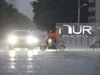 A citizen is riding in a rainstorm in Fuyang, China, on July 4, 2024. On the same day, Fuyang city in Anhui province is suffering heavy rain...