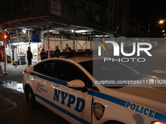 A New York City Police Department vehicle is blocking the roadway at the crime scene. One person is being assaulted, and one person is being...