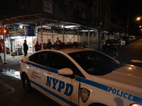 A New York City Police Department vehicle is blocking the roadway at the crime scene. One person is being assaulted, and one person is being...