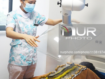 A doctor in the department of acupuncture and massage at a traditional Chinese medicine hospital is giving a person a moxibustion to help hi...