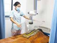 A doctor in the department of acupuncture and massage at a traditional Chinese medicine hospital is giving a person a moxibustion to help hi...