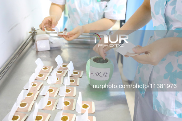 A doctor of acupuncture and massage is making ''Sanfu paste'' at a Traditional Chinese Medicine hospital in Chongqing, China, on July 3, 202...