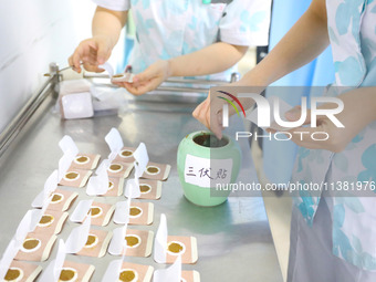 A doctor of acupuncture and massage is making ''Sanfu paste'' at a Traditional Chinese Medicine hospital in Chongqing, China, on July 3, 202...