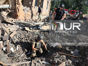 Law enforcers are examining the crater from an impact in a residential area after the Russian glide bomb attack in Kharkiv, Ukraine, on July...