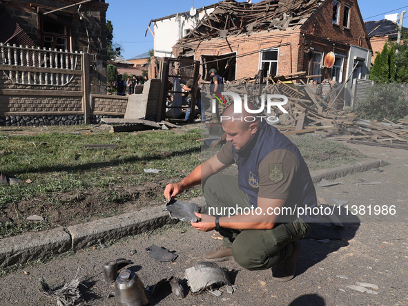 A Prosecutor's Office employee is holding a fragment of a Russian munition in a residential area after the Russian glide bomb attack in Khar...