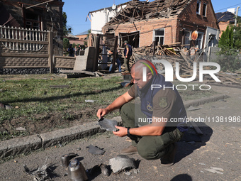 A Prosecutor's Office employee is holding a fragment of a Russian munition in a residential area after the Russian glide bomb attack in Khar...