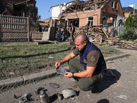 A Prosecutor's Office employee is holding a fragment of a Russian munition in a residential area after the Russian glide bomb attack in Khar...