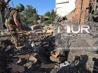 Law enforcers are examining the crater from an impact in a residential area after the Russian glide bomb attack in Kharkiv, Ukraine, on July...