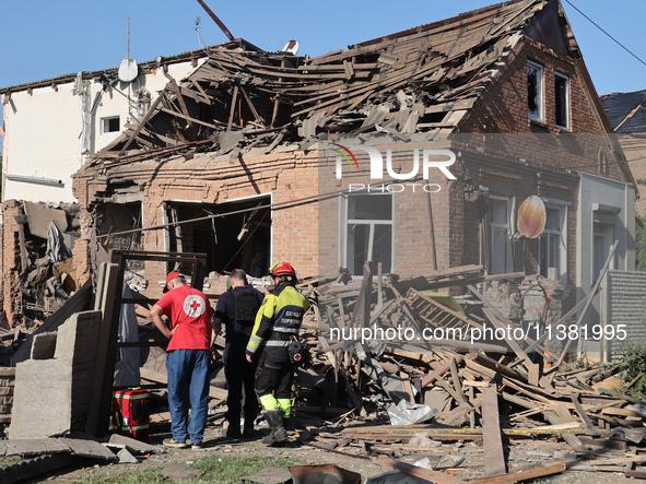 Rescuers, a police officer, and a Ukrainian Red Cross representative are standing outside a house destroyed by the Russian glide bomb attack...