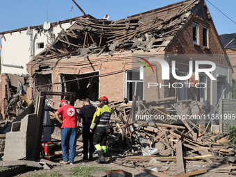 Rescuers, a police officer, and a Ukrainian Red Cross representative are standing outside a house destroyed by the Russian glide bomb attack...