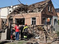 Rescuers, a police officer, and a Ukrainian Red Cross representative are standing outside a house destroyed by the Russian glide bomb attack...