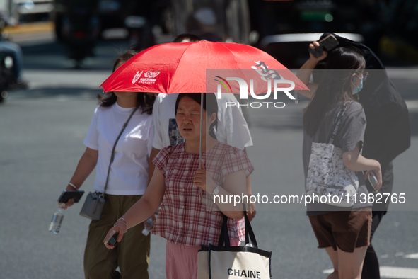 People are walking across the street during the heatwave in Shanghai, China, on July 4, 2024, as the temperature reaches 39 degrees Celsius 