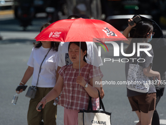 People are walking across the street during the heatwave in Shanghai, China, on July 4, 2024, as the temperature reaches 39 degrees Celsius...