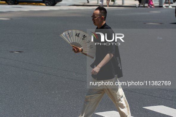 People are walking across the street during the heatwave in Shanghai, China, on July 4, 2024, as the temperature reaches 39 degrees Celsius 